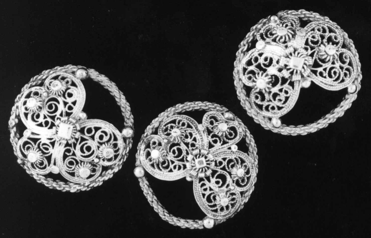 Malje i førgylt sølv, rund flettet ring utfylt av 3 delt bladform (hevet).