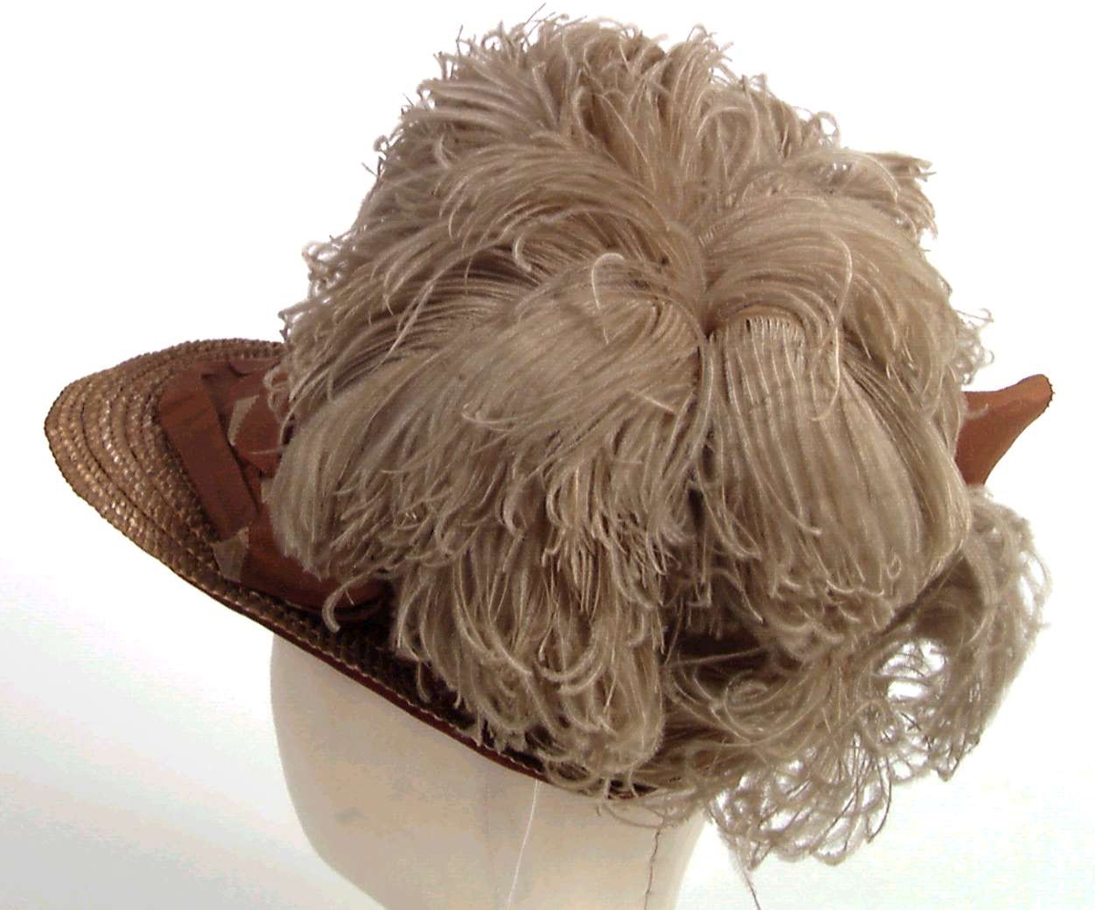 Strå hatt med dekor av ripsbånd og fjær, fôr av hvit silke.
