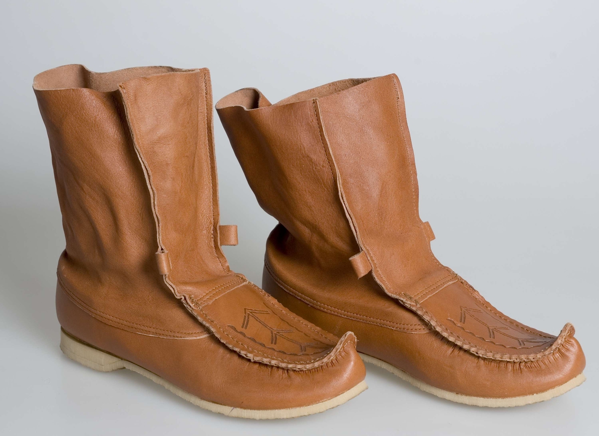 Et par sko eller komager,  overdel er av skinn og ligner tradisjonelle samiske komager, men skoene har gummisåle og er fabrikklaget.