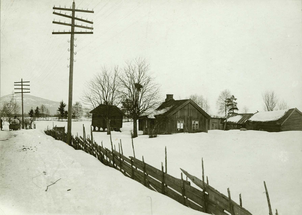 Plassen Vengerflaen, Eidsvoll, Øvre Romerike, Akershus. Husmannsplass sett fra vei om vinteren. Lysstolper og skigard langs veien.
