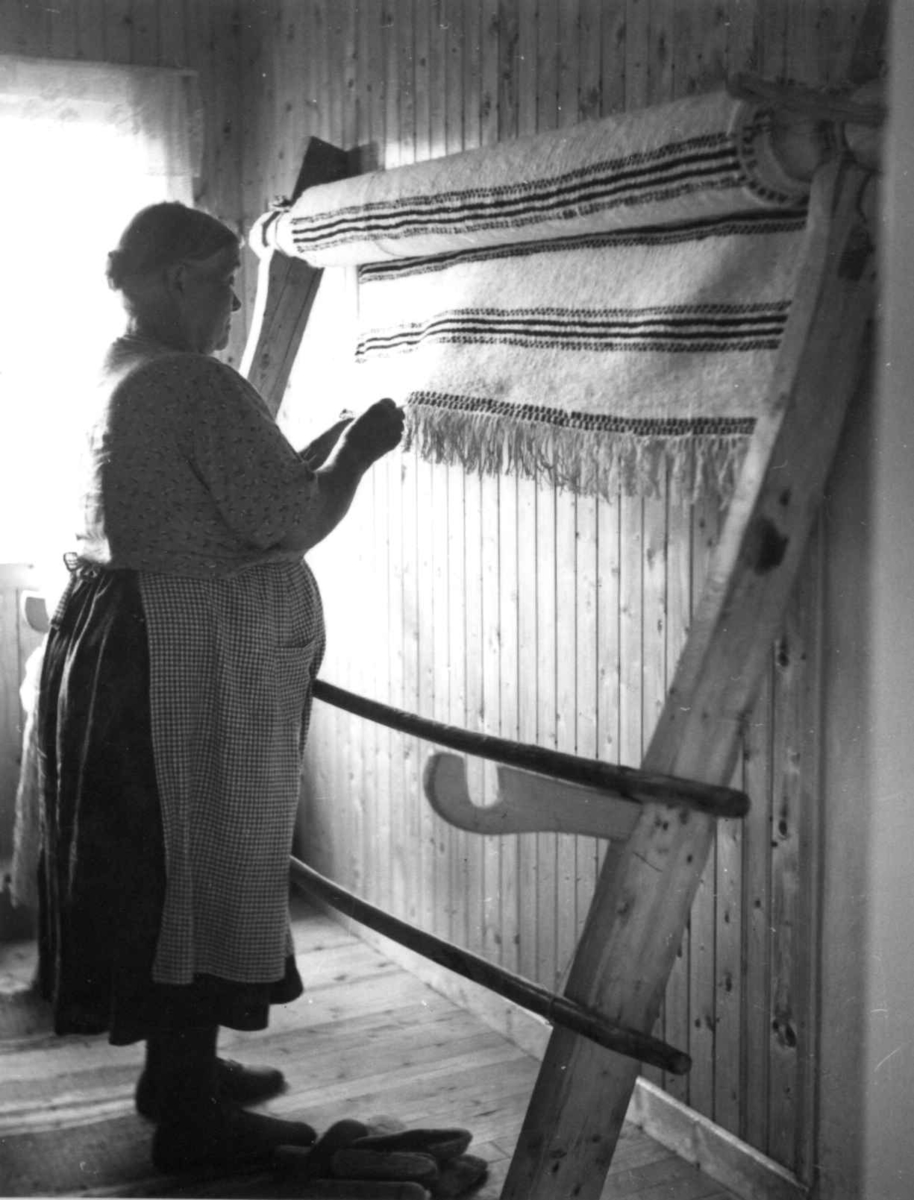 Greneveving (30). Anne Hansen er ferdig med greneteppet og holder på med demonteringen. Manndalen 1955.