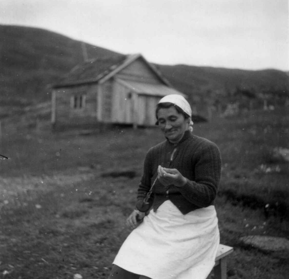 En kvinne spinner garn på hånftein. Marøyfjord 1949.