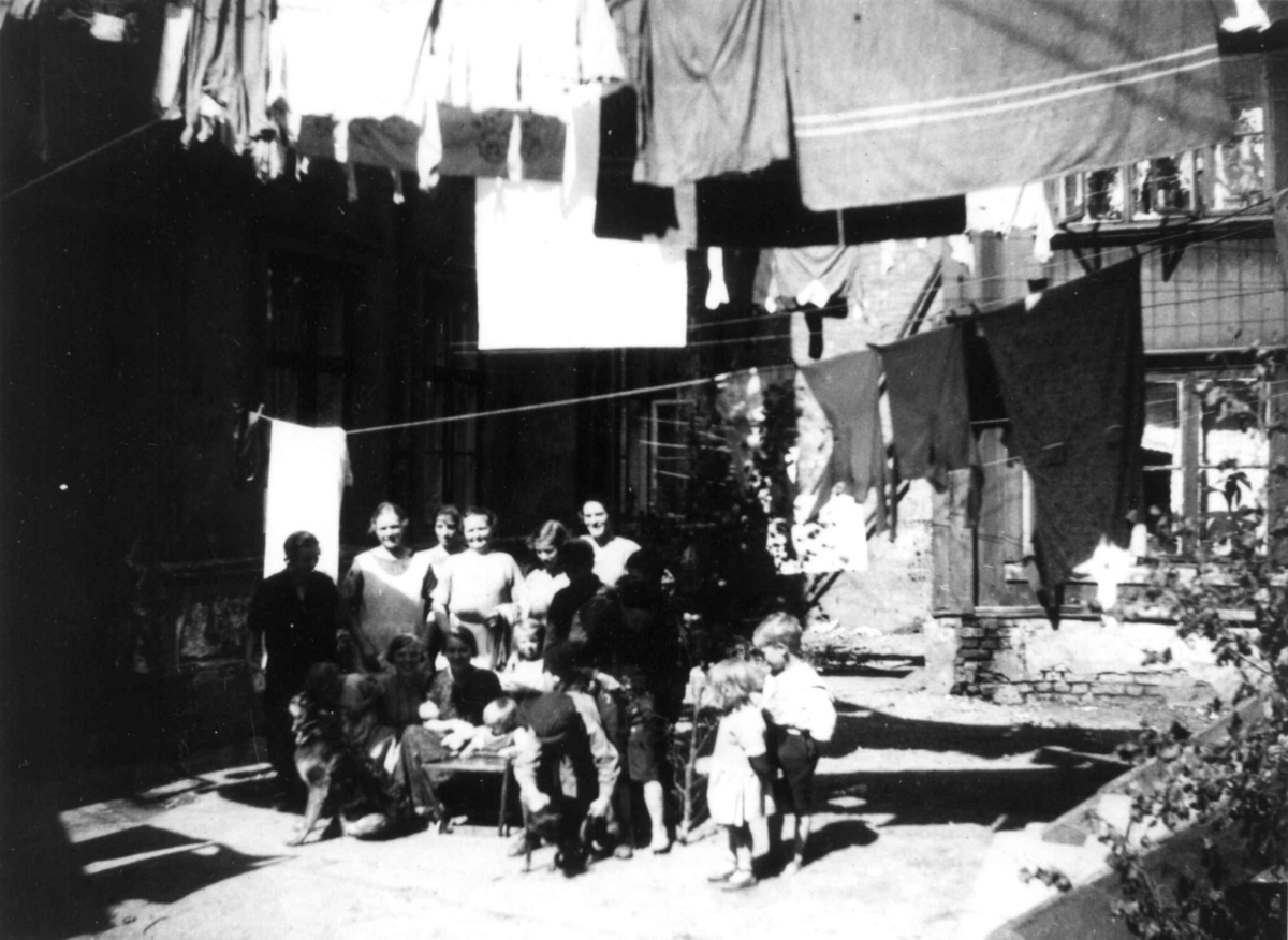 Fra gårdsrom, Oslo. Kvinner og barn poserer i gården under klesvask.
Fra boliginspektør Nanna Brochs boligundersøkelser i Oslo 1920-årene.