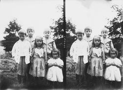 Fem barn oppstilt for fotografering utendørs, ukjent sted.