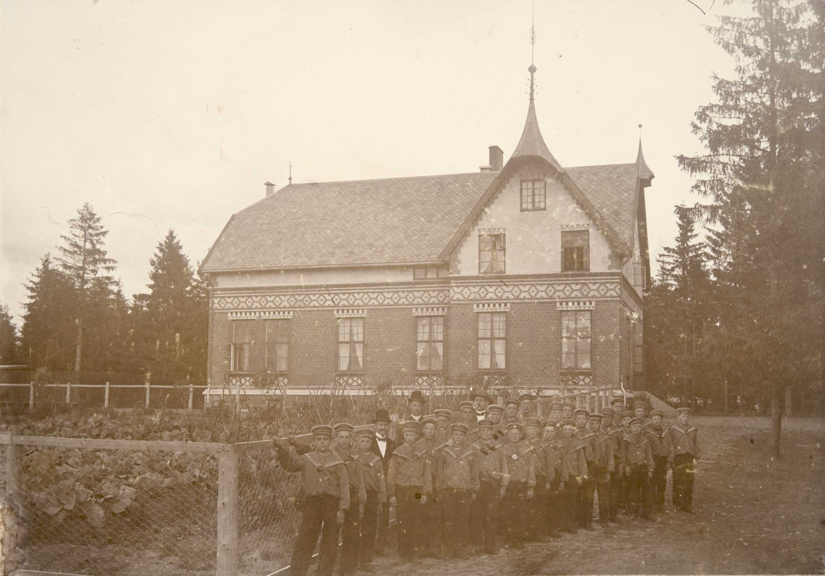 Internatbygningen Breidablikk på Bastøy skolehjem, Bastøya, ca. 1903. Elever står oppstilt utenfor bygningen.