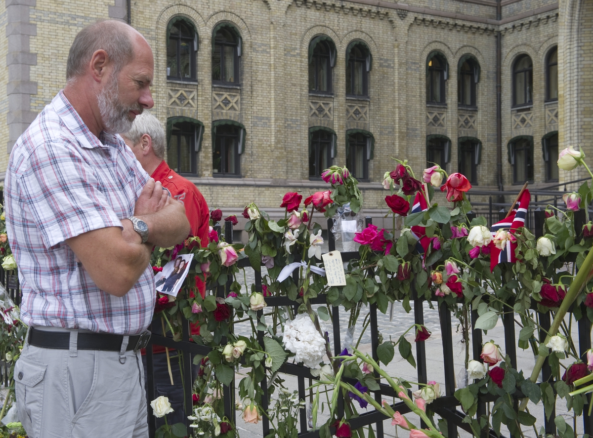 "Sorg i det offentlige rom". Folk ser på blomster og hilsener utenfor Stortinget.