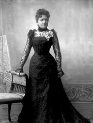 Portrett, kvinne i svart kjole med chiffonermer. Fru Erbe.