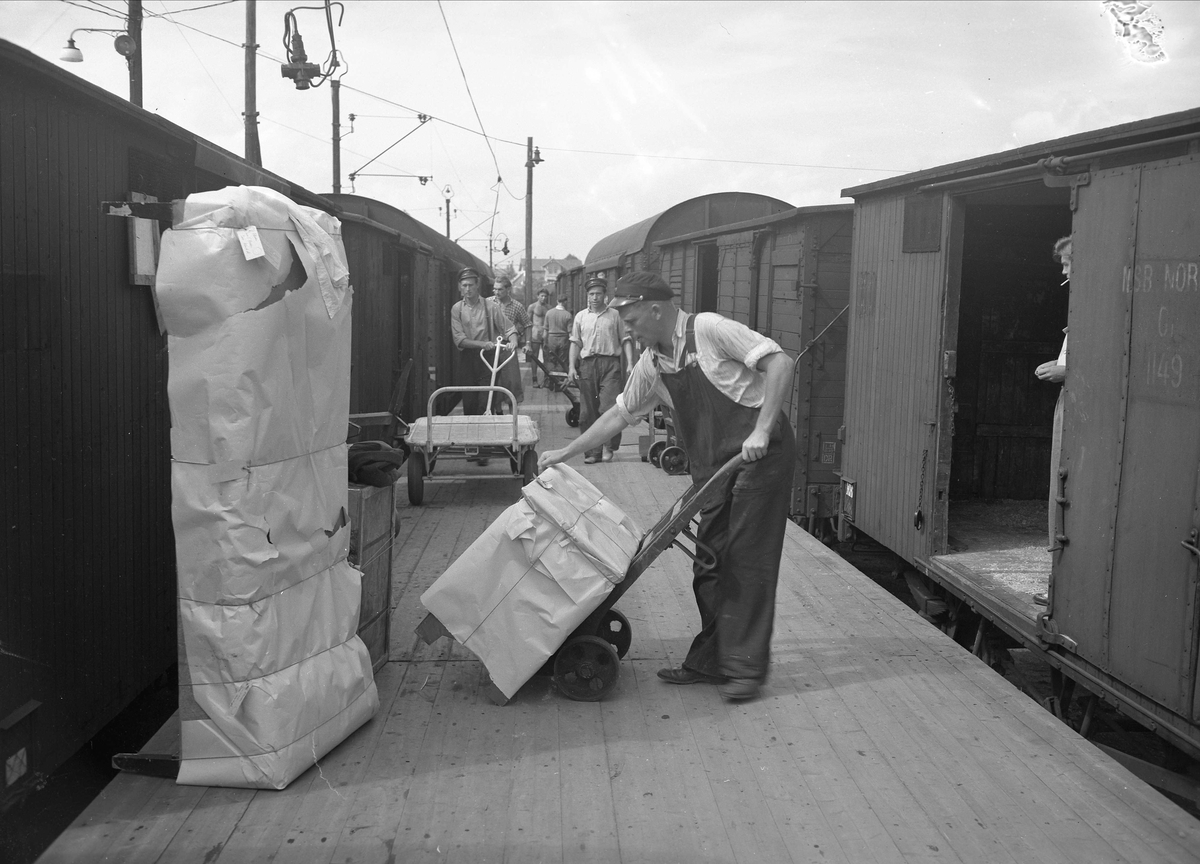 Drammen jernbanestasjon, Drammen, 1950-tallet. Mann som laster gods inn i godsvogn.