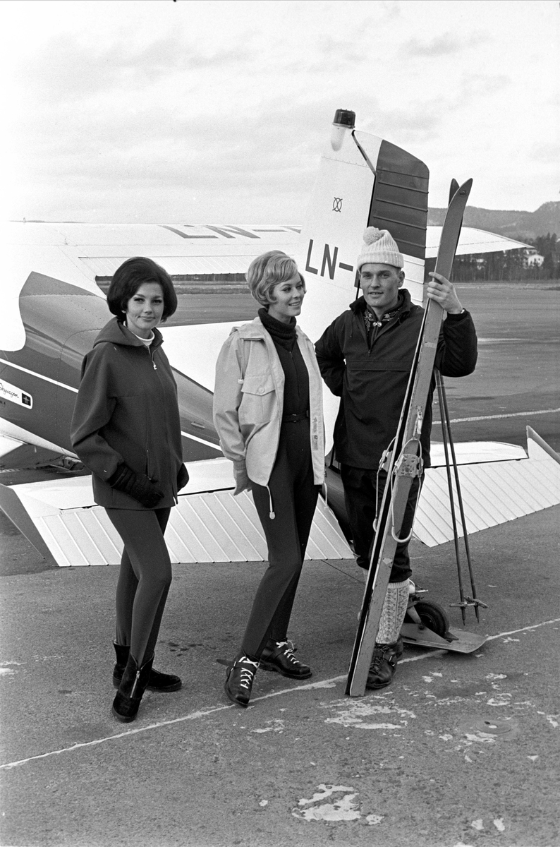 Mannekenger til fjells med fly, november 1965. Mennesker med ski foran fly.