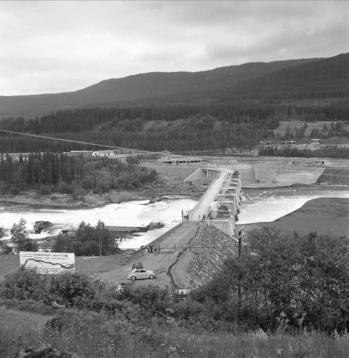 Utbygging av Hunderfossen kraftverk, Gudbrandsdalen, Lillehammer, Oppland, august 1962. Oversiktsbilde av elv, anlegg/bro og elva.