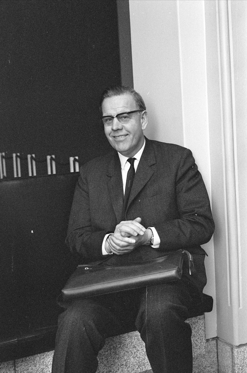 Fra Stortinget, Oslo oktober 1965. Mann sittende med dokumentmappe på fanget.