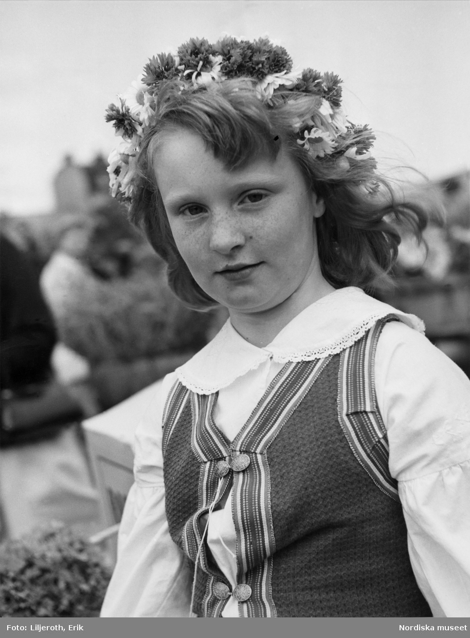 En ung flicka i folkdräkt och med blommor i sitt hår. Blekinge.
