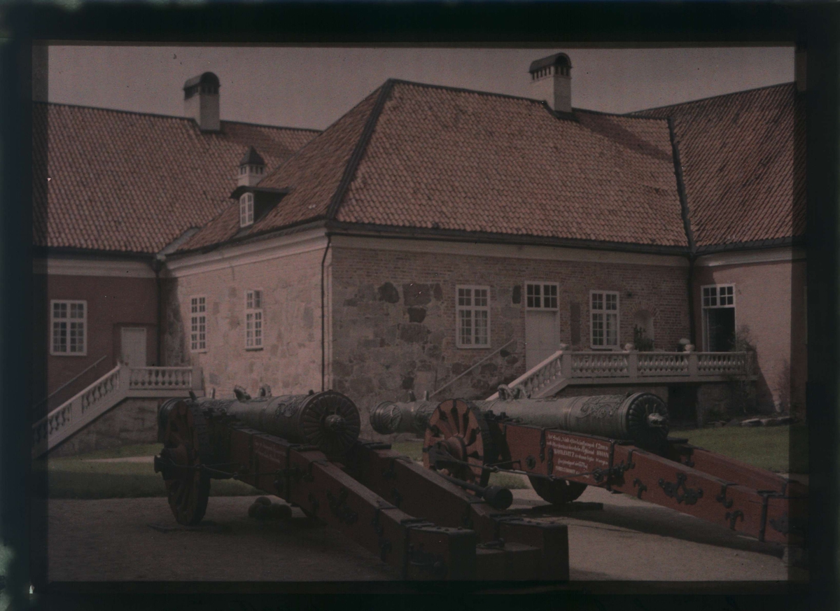 Yttre borggården på Gripsholms slott. "Suggan och Galten", kallas de stora kanonerna i förgrunden. Till vänster köket, i bakgrunden till höger en bit av den så kallade kavaljersflygeln som Gustav III lät uppföra. Autochrome / Autokromfotografi.
