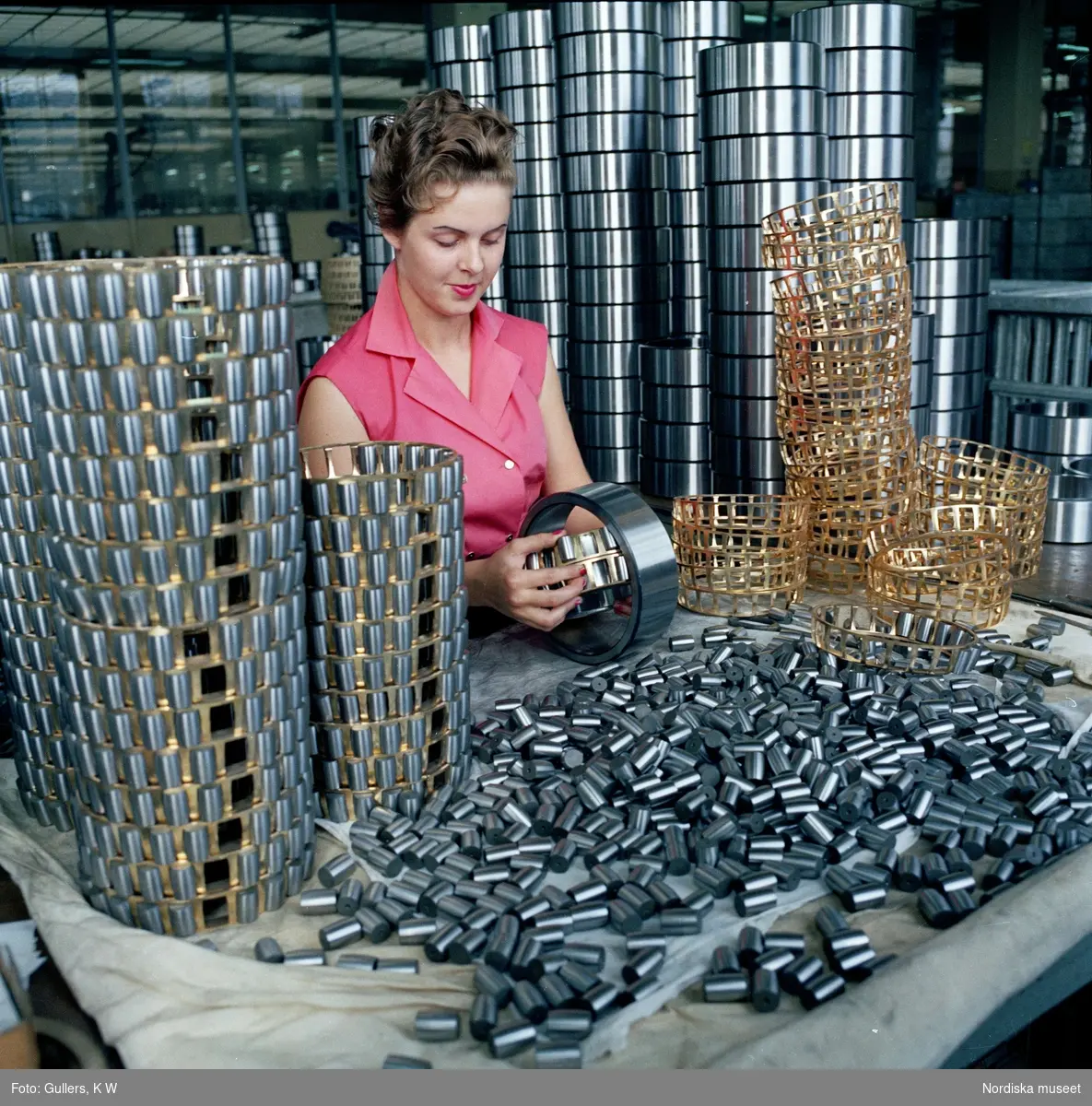 Interiör från SKF:s kullagerfabrik i Göteborg. Kvinna monterar ihop delar till rullager.