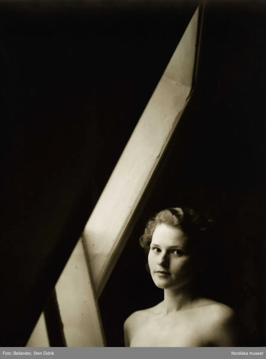 Porträtt av ung kvinna i ljuset av ett vindsfönster.