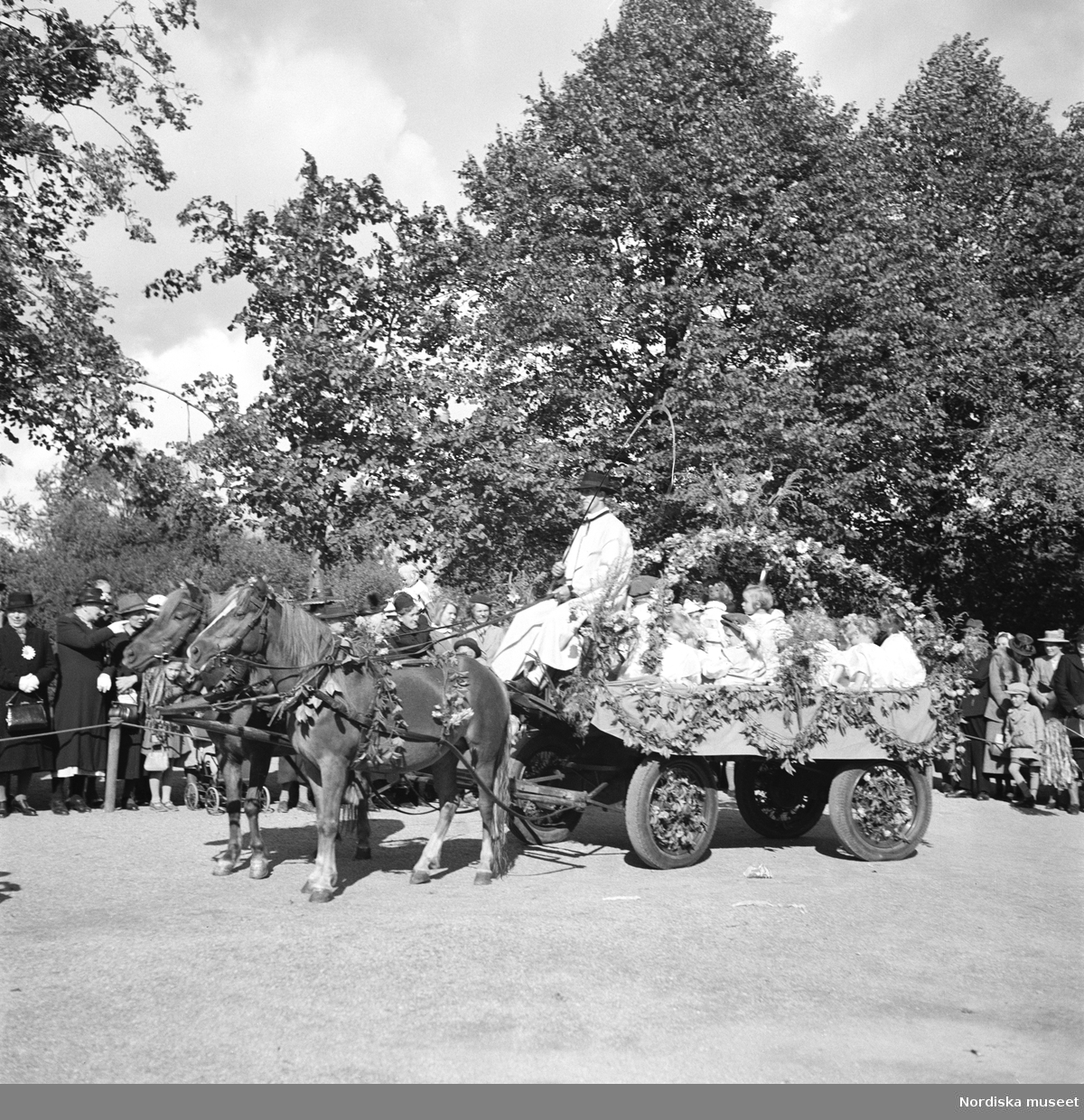 Barnens dag på Skansen 6 sept 1942. En öppen lövad vagn full av barn bakom förspända hästar  i procession.