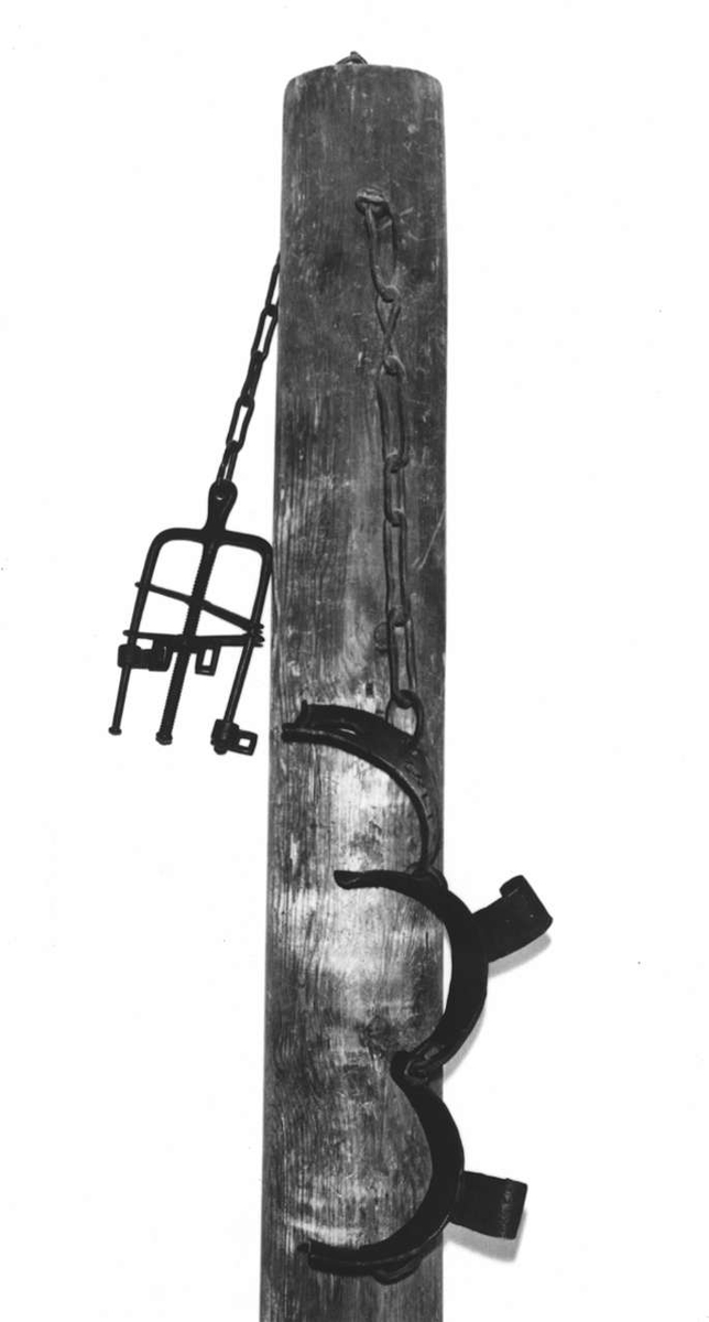 Straffstock med hälsjärn och handbojor. Stocken står på en fotplatta av trä. I dess topp är fästade ett halsjärn med låsanordning och gaffelformade handbojor med skruv. På halsjärnet stämplat årtalet: 1782.