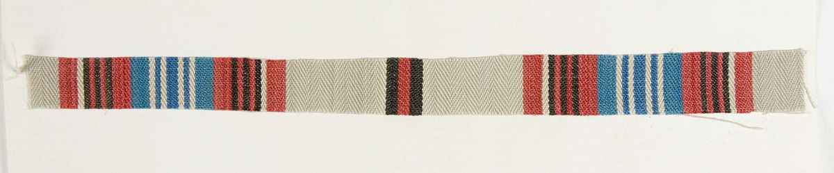 Vävprov ämnat för bolstervarstyg vävt med bomullsgarn i kypert. Randigt i beige, rött, blått, vitt, svart och brunt. Vävprovet är uppklistrat på en kartong i storleken 22 x 28 cm. I övre högra hörnet finns en stämpel "Uppsala läns hemslöjdsförening" och ett handskrivet nummer, "A.1636".