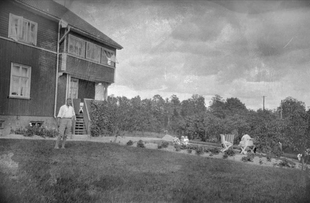 Man framför bostadshus, sannolikt Uppland 1940 - 50-tal