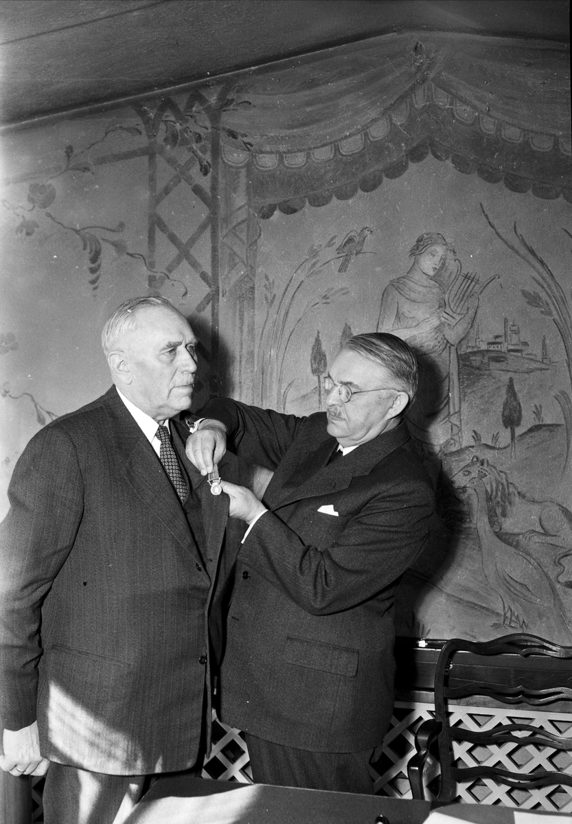 Landshövding Hilding Kjellman fäster medalj på äldre mans kavaj, Uppsala, sannolikt 1952