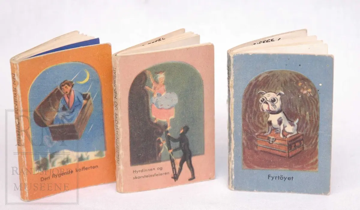 tre eventyrbøker av H. C. Andersen i minatyrstørrelse.
a) Den flygende kofferten
b) Hyrdinnen og skorsteinsfeieren
c) Fyrtøyet