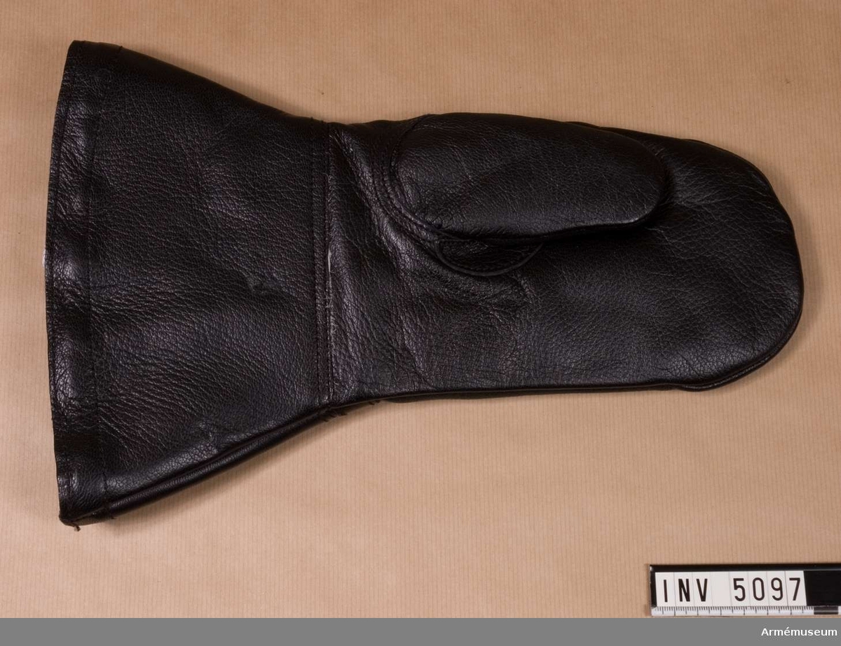 Handske, motor-, av svart läder. Motorhandske tillverkad hos John A Hörnell 1977. Är storlek 2 och har kronstämpel. Foder i form av en löstagsbar handske i grön syntetpäls, fastsatt med kardborrband.