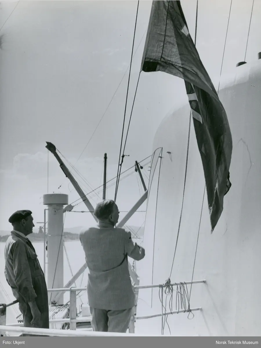 Direktør Aamundsen heiser flagget på cargolineren M/S Burrard, B/N 508 under prøvetur i Oslofjorden 12. juli 1956 (?). Skipet ble levert av Akers Mek. Verksted i 1956 til Fred. Olsen & Co.