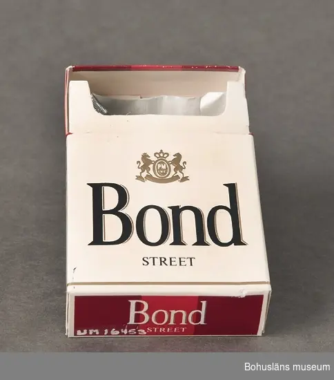 Tom cigarettförpackning av märket "Bond". Vitt, svart och rött tryck.
Varningstext på ena sidan: Kärlsjukdomar. Vid kärlsjukdomar är det viktigt att sluta röka. Socialstyrelsen.