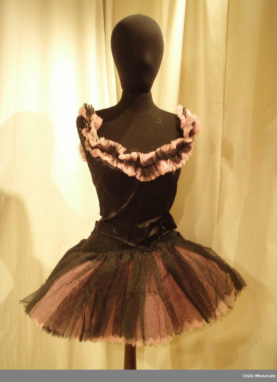 4 balettkjoler, korte, med liv i sort silke og kant i rosa og sort tyll, skjørtdel i mange lag rosa og sort tyll. 4 vifter i rosa/sort tyll, 4 viter i rosa tyll. 1 hodepynt i samme stoff og farger.
