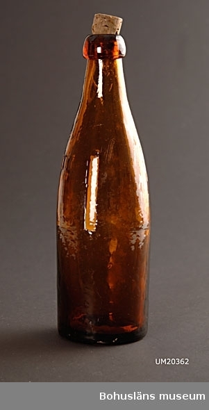 Flaska för 1/3 liter i brunt glas och med naturkork. 
På halsen  gjutet i relief ett " L " inom tre stjärnor och "1/3 lit". Formar från Liljedahls glasbruk, övertagna av Surte glasbruk.
I botten "1900.21" för årtalet 1921.