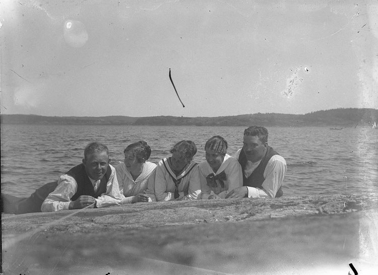 Enl. text i blå bok: "Tre damer och två män liggande på strand."