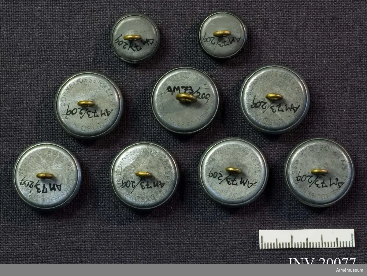 Nio knappar i två olika storlekar, av grå metall dekorerade med ett solkors krönt av en örn. Nasjonal Samling, Norge (1940-45), 7 större och och 2 mindre delar.
