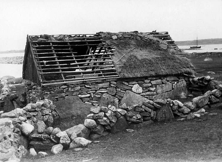 Skrivet på baksidan: "Halland, Viske hd, Värö sn., Båtfjorden. Söabo, märk tångtäckningen av ryggåsen. Muren tätad med tång (grästång). I sådana hus drevs förr fåren in under sommarnätterna av "söakären".
