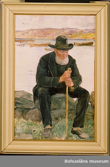 Olaus Dahlström, Sannäs, född 1825.
Äldre man med käpp och i mörka kläder och hatt. Han sitter på sten vid strand. I bakgrunden fjord med brygga och båtar.