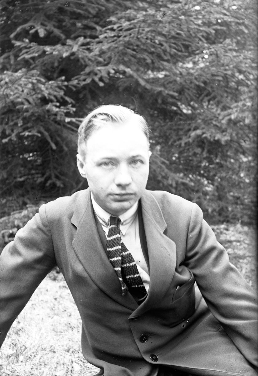 Porträtt av fotograf Gustav Andersson från Jönköping, i bakgrunden syns granar.