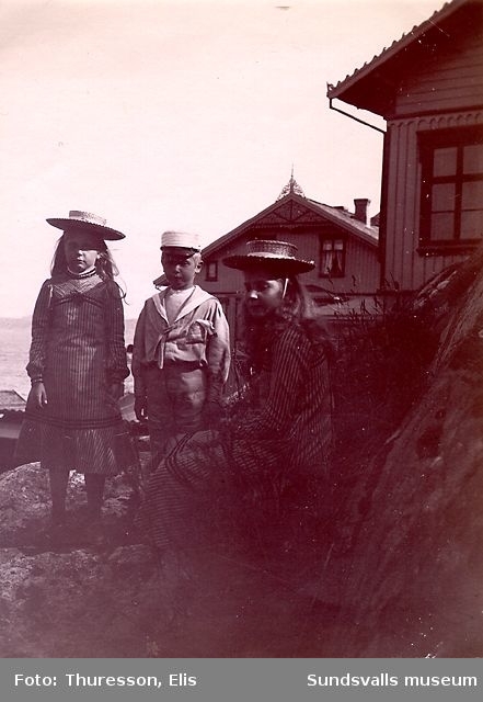 Två flickor och en pojke med bostadshus i bakgrunden.