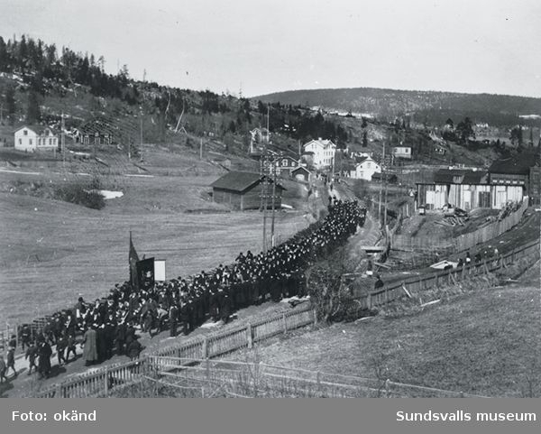 Demonstrationståg i samband med hungeråret 1917. Här passerar man Gångviken på väg mot Sundsvall. På plakatet i demonstrationståget står ”Militarismen måste - - (dö?) så folket skall kunna leva!”.