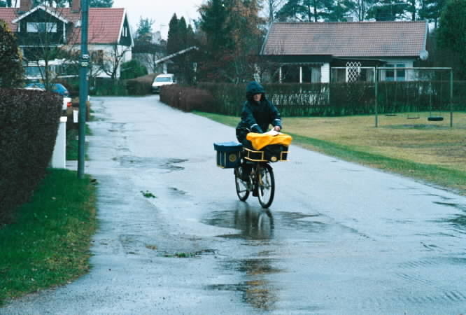Cyklande brevbärare i Knivsta, med regnskydd både för kropp och post.