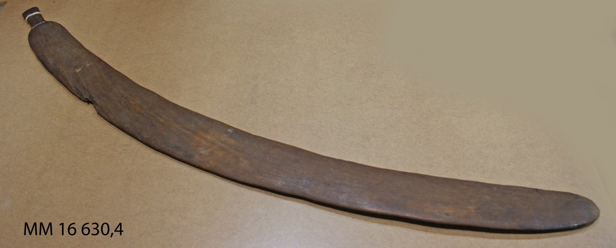 Uthuggen ur ett stycke brunt trä. Format som ett böjt svärd, lika bertt hela vägen. Hantag (cirka L=8 cm) smalare än resten av svärdet. (Data: Nr 5:1:8 i Hartvig Fleeges katalogisering