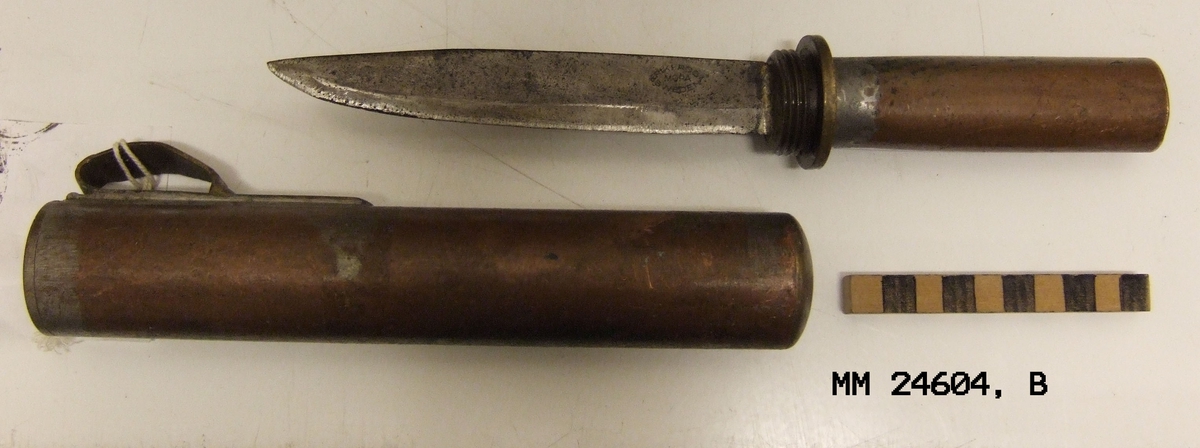 Balja (slida) till dykarkniv från 1900-talets första hälft. Tillverkad av koppar, mässing och stål. Kniven skruvas ihop med en cylindriskt gängad balja (slida). Bladet på kniven är märkt "Erik Frost, Mora, Sweden".