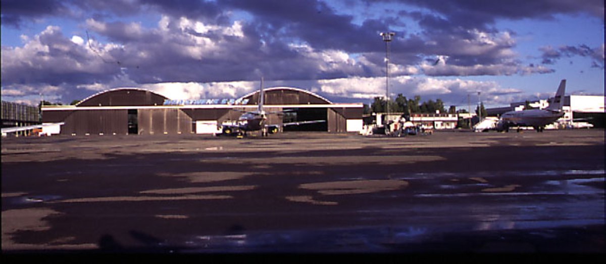 Lufthavn, 2 fly (fra Braathens) parkert foran hangarbygninger.