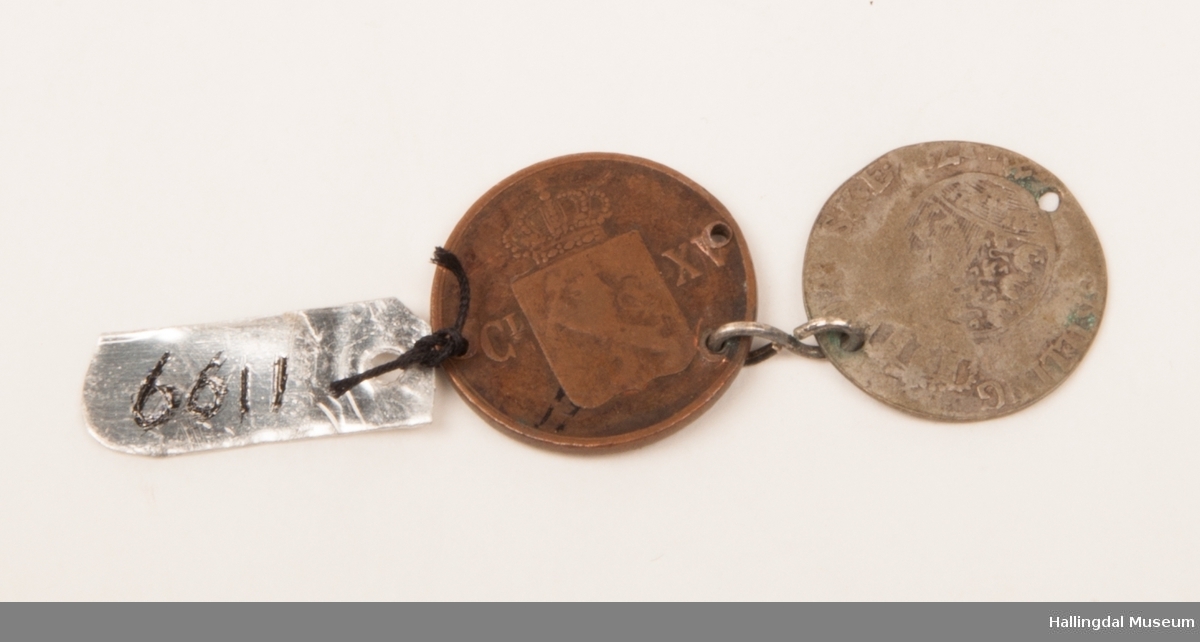 2 mynter henger sammen, del av et kjede.  Holdt sammen av 8-talls formet sølvtråd.  1 sølv 4-skilling, da., 1 1/2 skilling kobber 1863, sv.