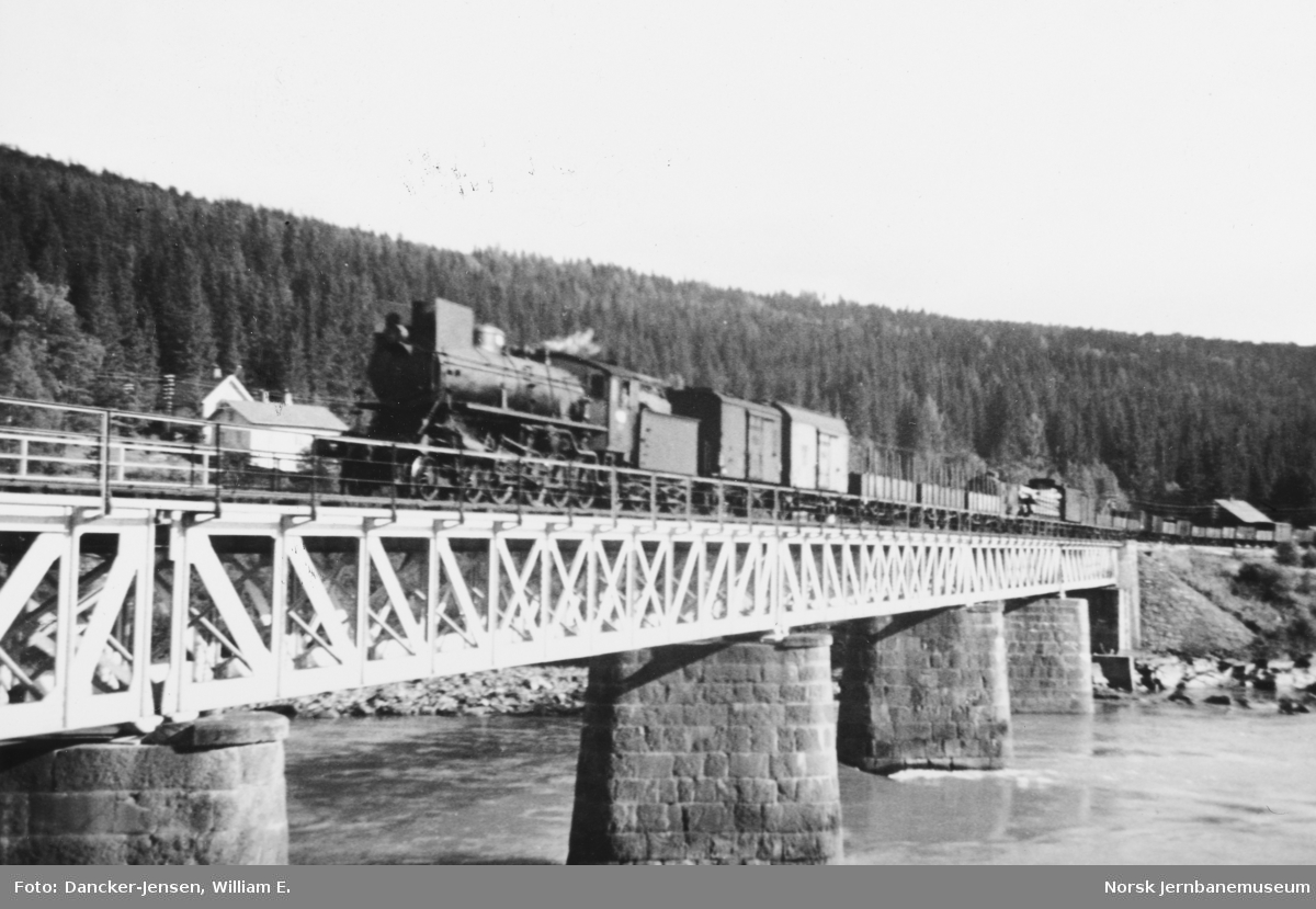 Brua over Lågen med Langsveen med passerende godstog trukket av damplokomotiv type 26a