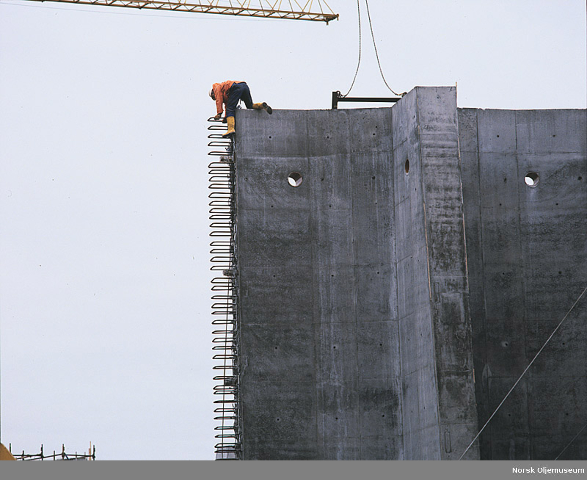 En mann klatrer på en del av beskyttelsesveggen til Ekofisk 2/4 T under byggingen i Ålfjorden.