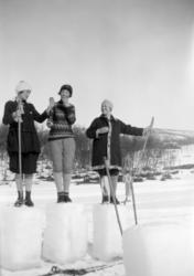 Tre kvinner i skiantrekk poserer oppå hver sin "pidestall" a
