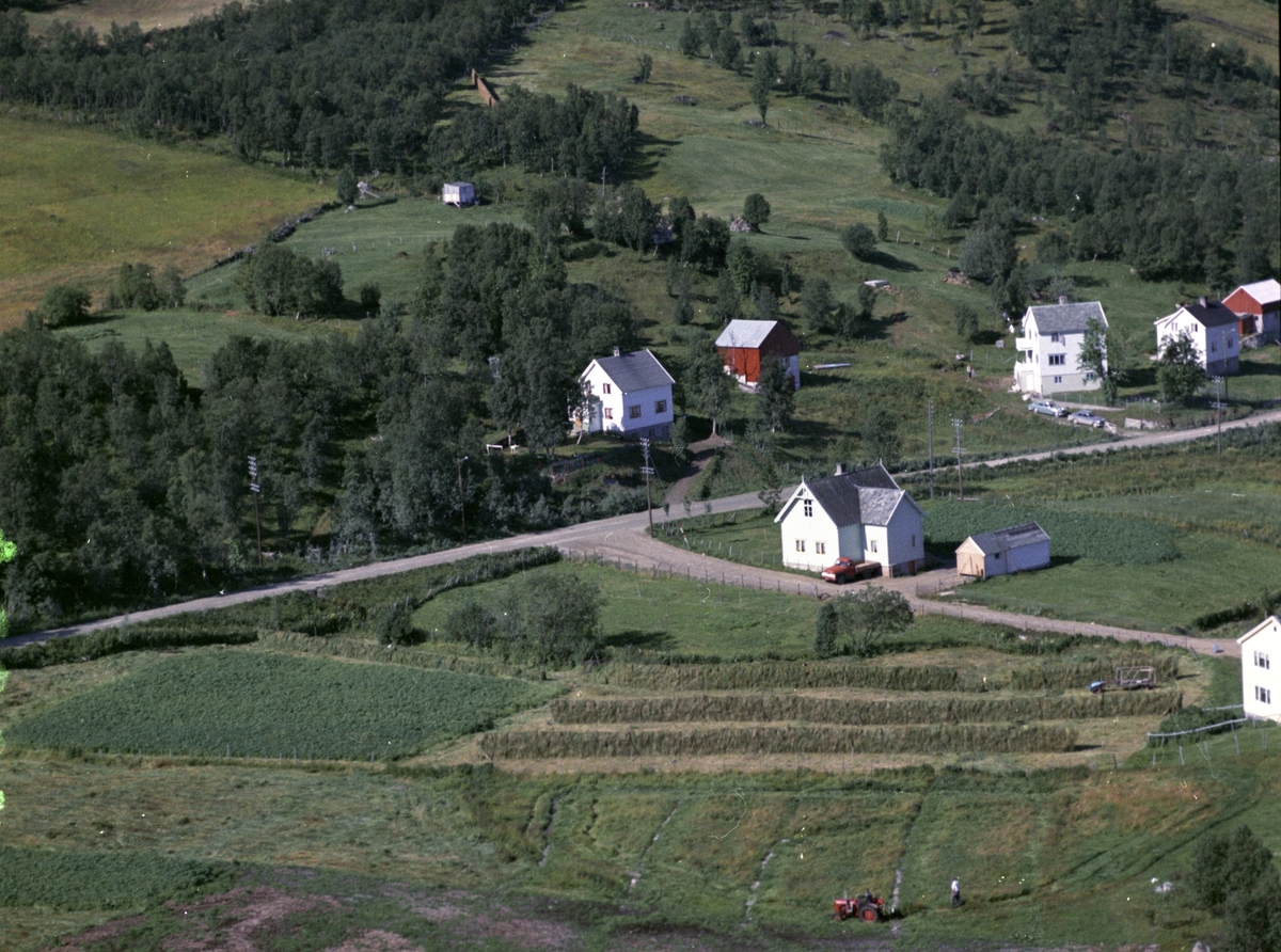 Flyfoto av gammelskolen i Fauskevåg. Hesjer og rød traktor i forgrunnen.