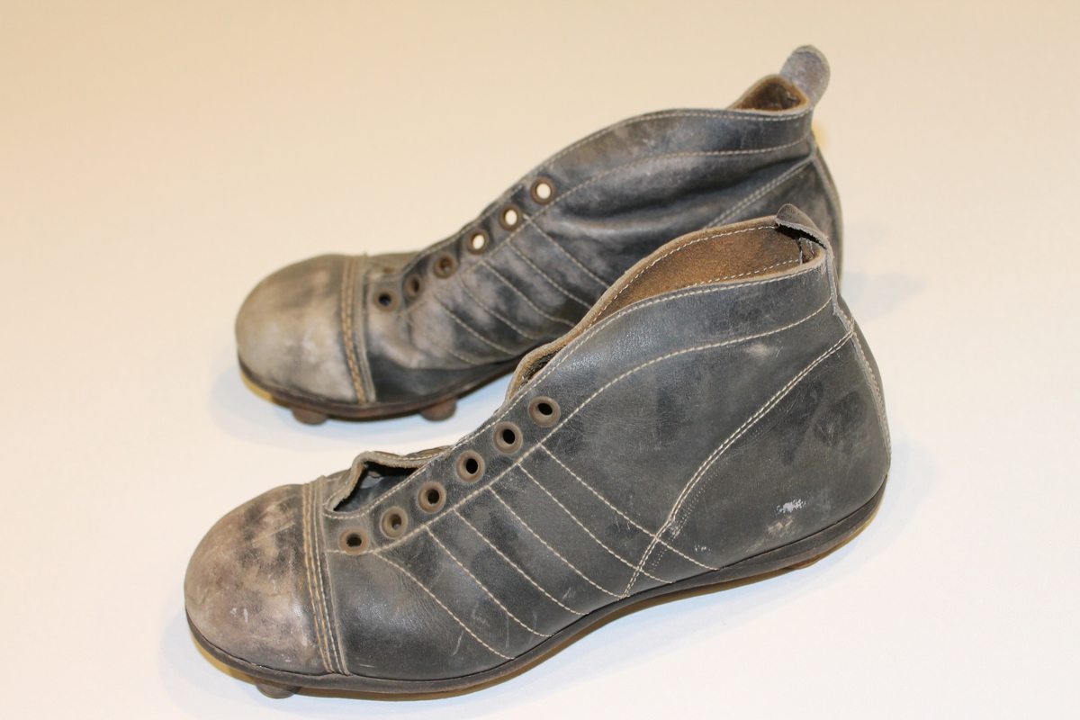 Par med brune fotballstøvler i lær fra 1940-50-tallet. Skoene er av typen man måtte smøre inn med vaselin. Knotter som er spikret på
