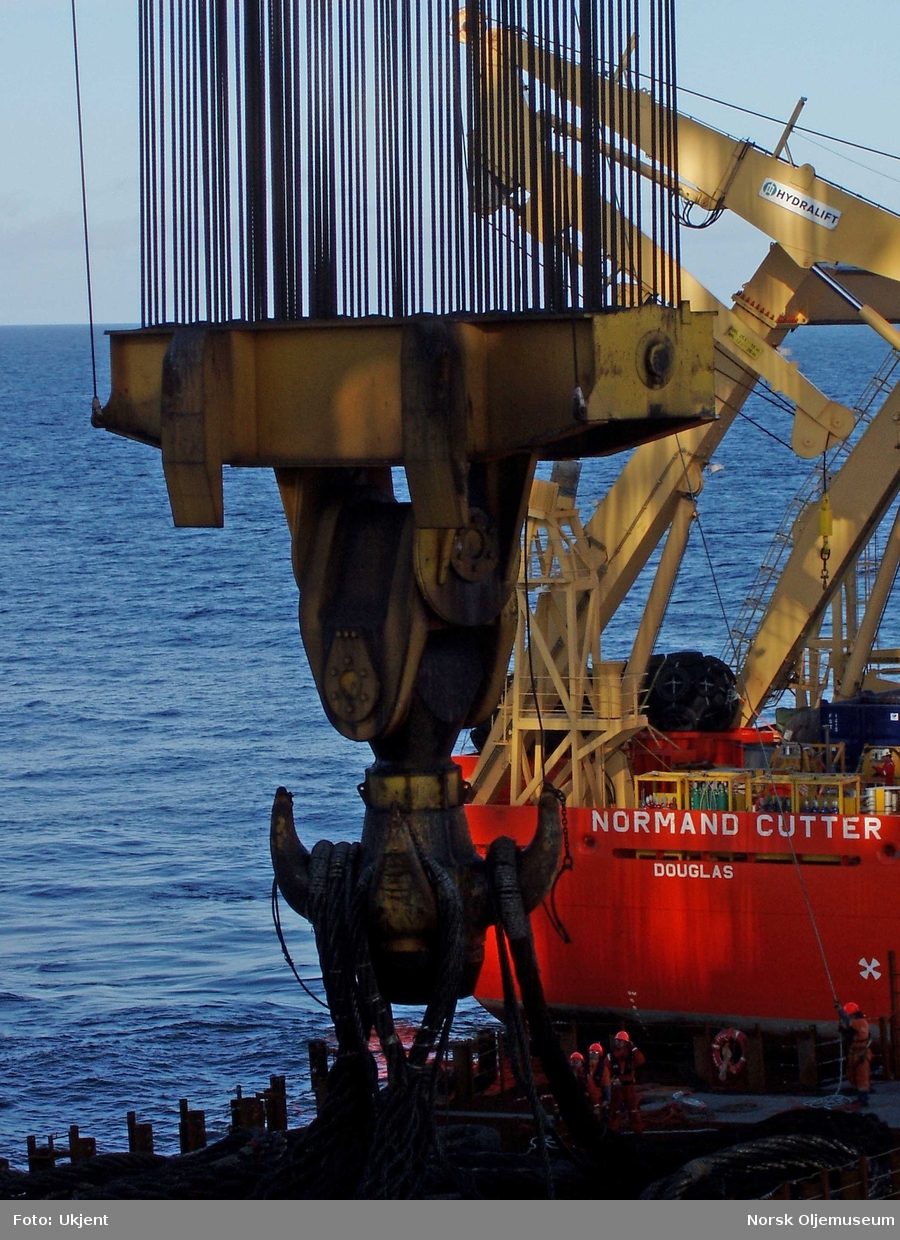 Det er store dimensjoner på løftekrok og wire ombord på kranlekteren Saipem 7000, som her er klar for å løfte understellet til DP 1 opp fra havbunnen.
Offshorefartøyet Normand Cutter - i bakgrunnen - bistår i arbeidet.
 