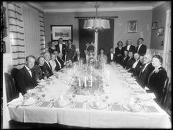 Gruppe, kvinner og menn festkledde rundt dekket bord, stuein