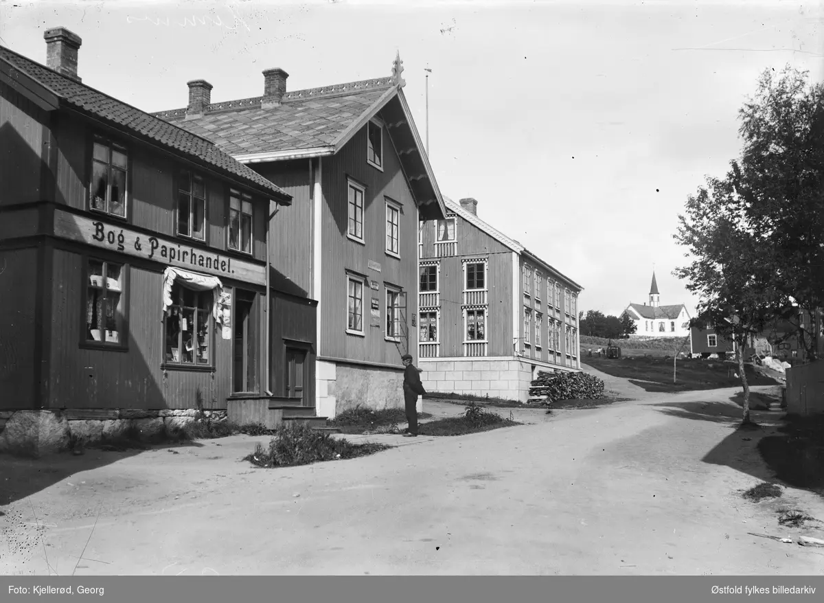 Hemnesberget i Nordland.
Skilt: Bog og papirhandel, huset til venstre. I bakgrunnen Hemnes kirke bygd 1872.